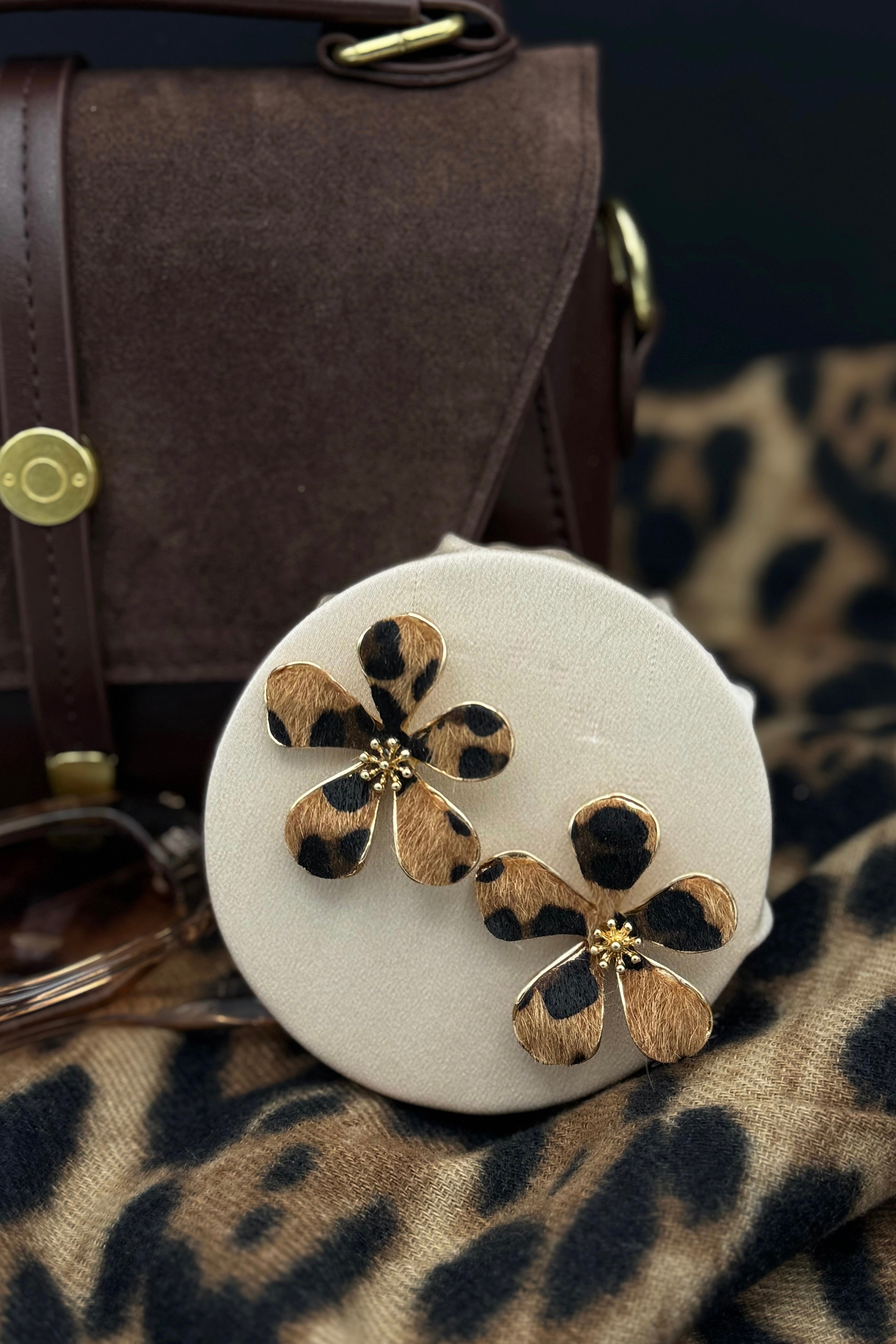 Boucles d'oreilles florales léopard dorées avec motifs délicats, bijoux femme tendance sur fond blanc