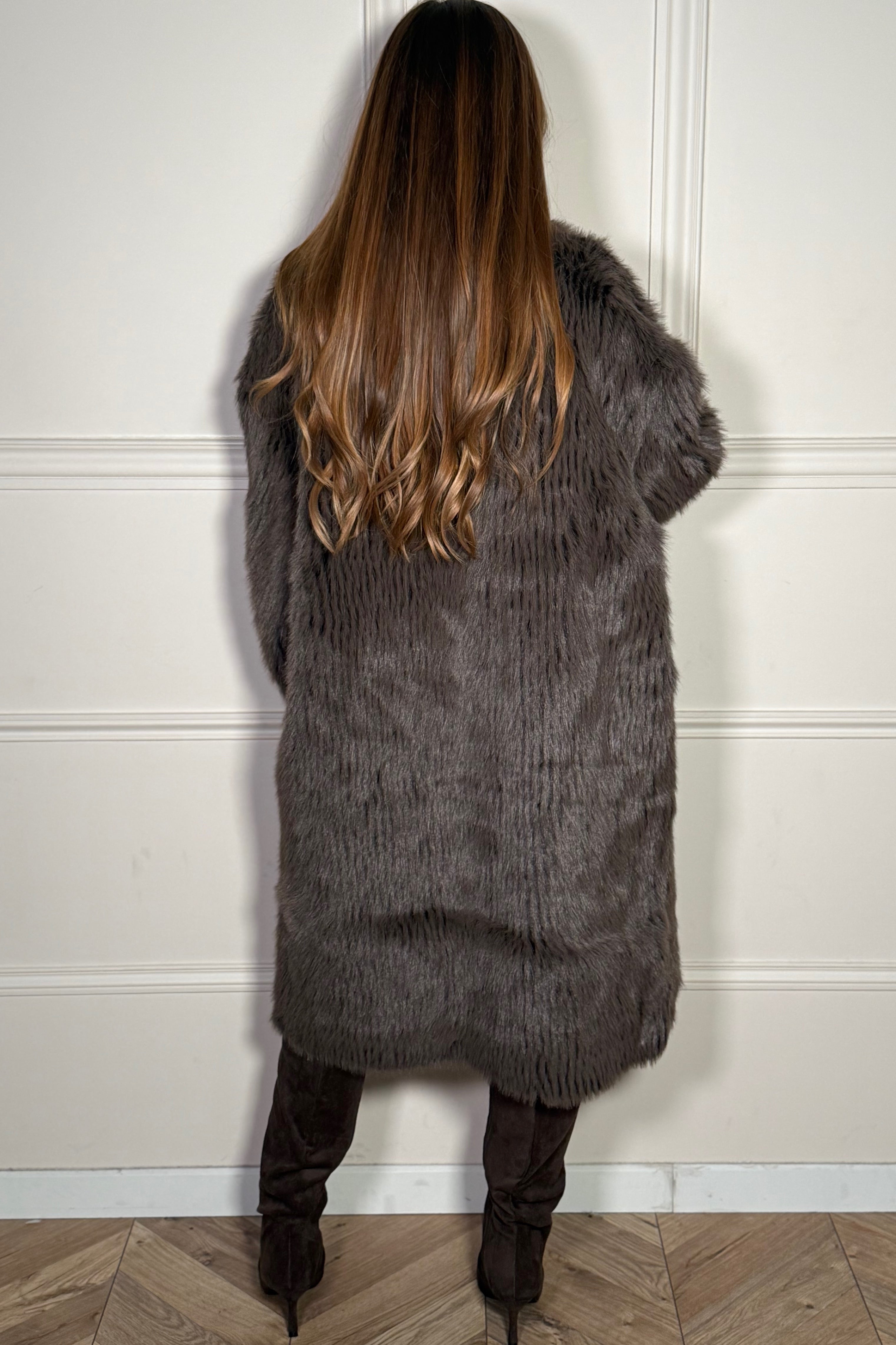 Vue de dos du manteau long en fausse fourrure, soulignant la longueur protectrice et la silhouette élégante