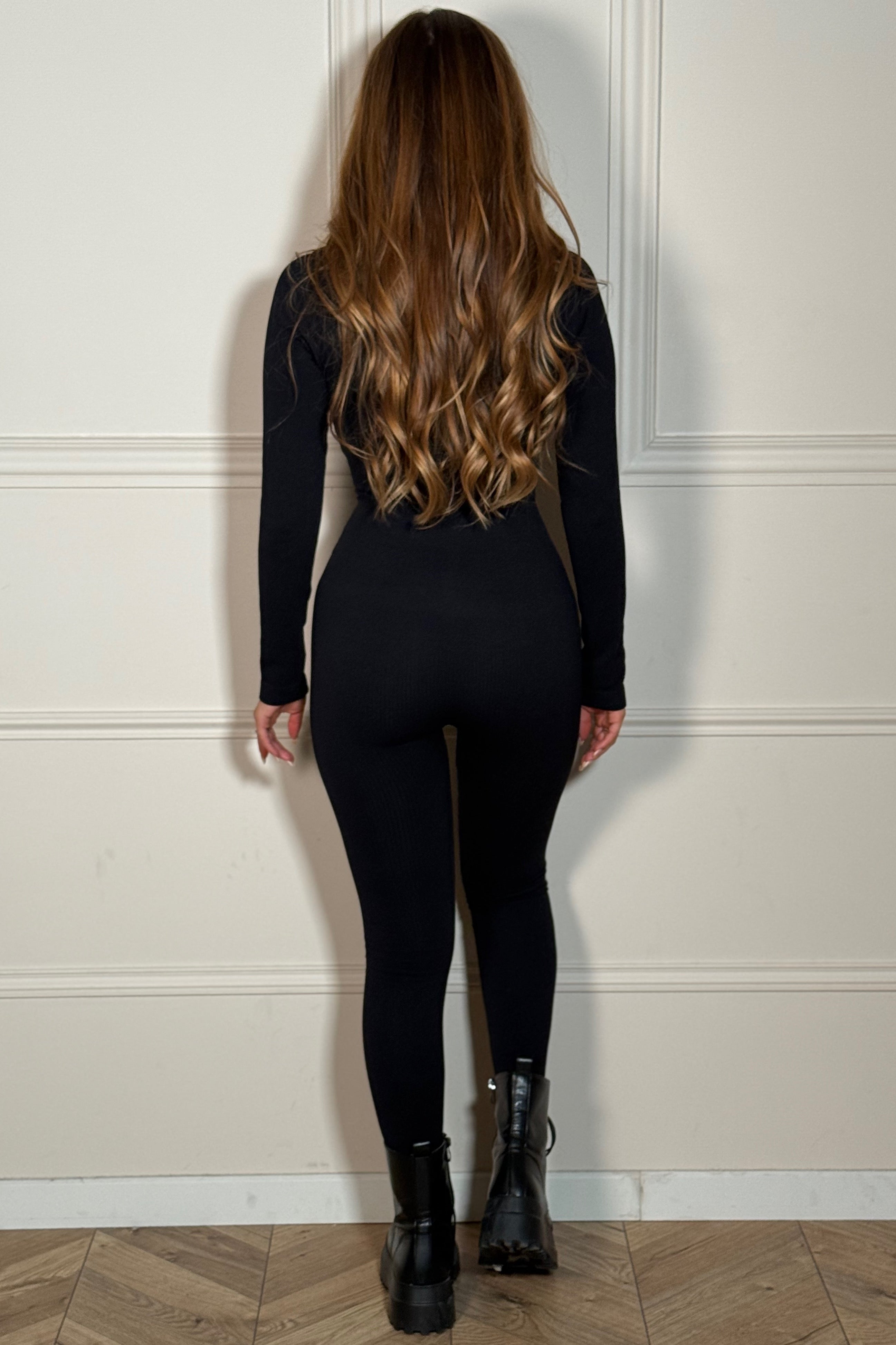 Femme élégante en combinaison gainante côtelée col zip dans un environnement moderne, look décontracté chic