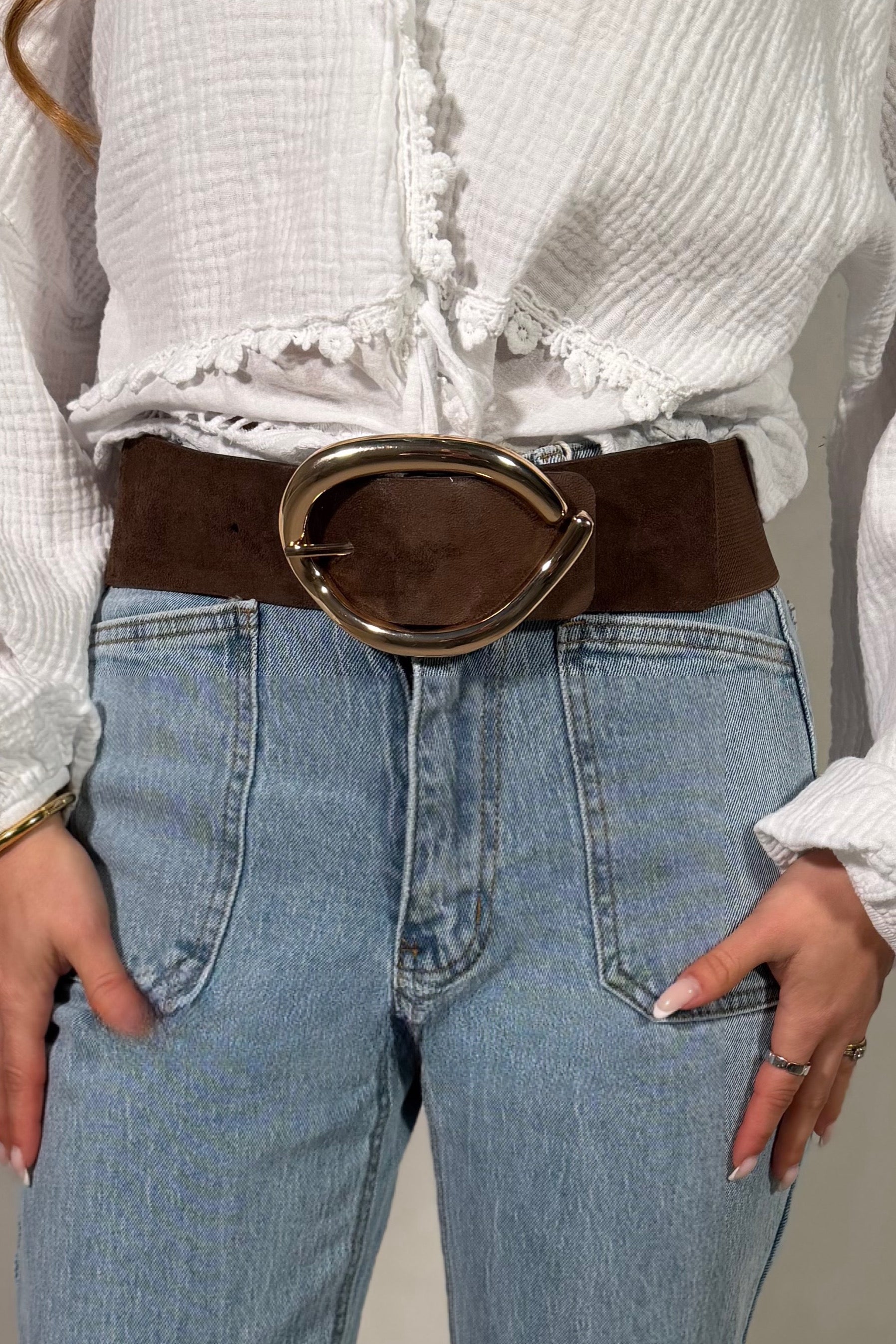 Ceinture en suédine marron avec bande élastique et boucle métallique, fond blanc